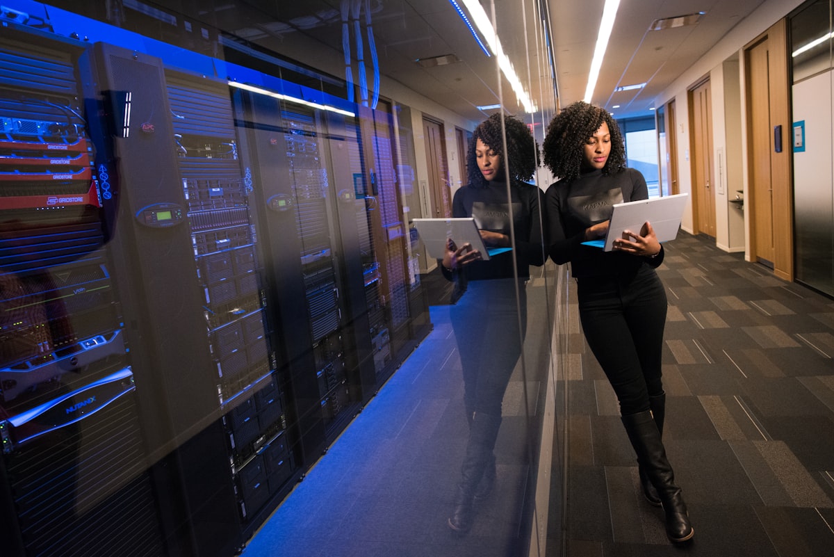 Engineer reviewing a laptop beside a glass-walled server room